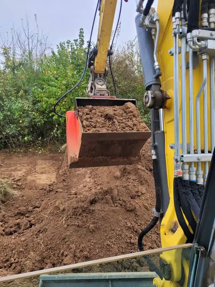 Bagger bei Aushubarbeiten auf einer Baustelle im Grünen