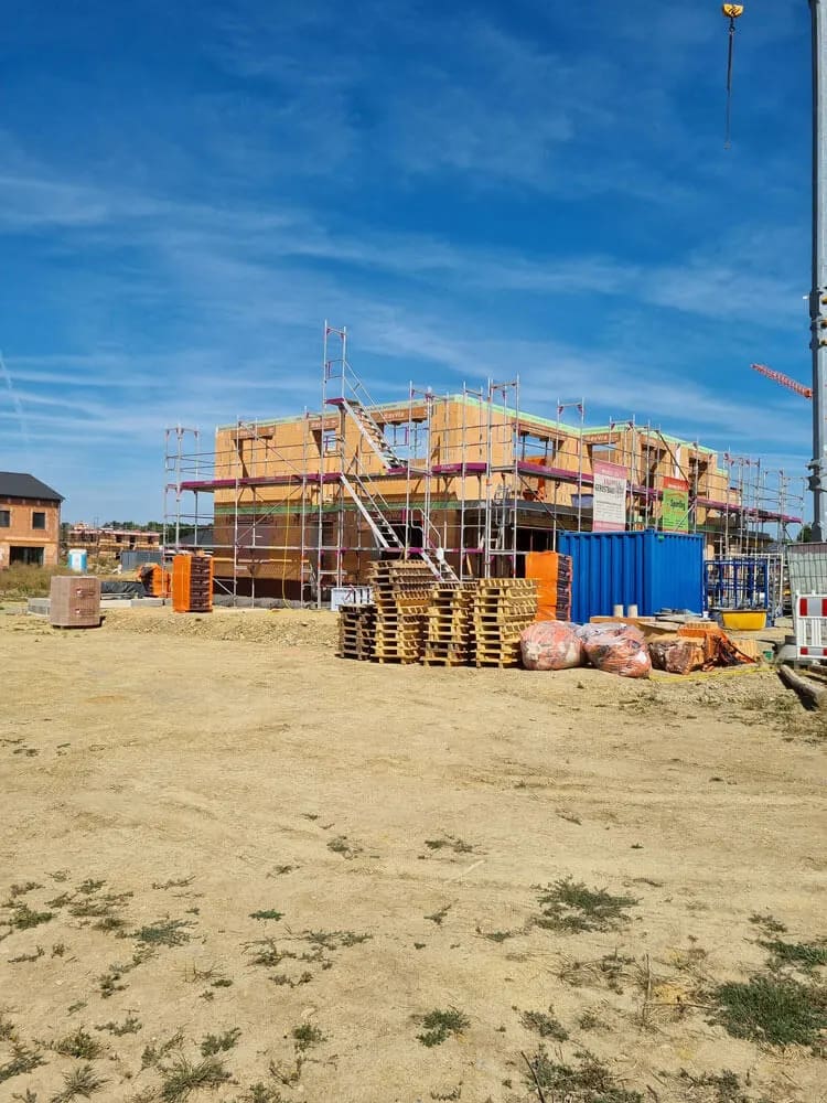Baustelle eines modernen Wohnhauses mit Baugerüst bei strahlendem Himmel